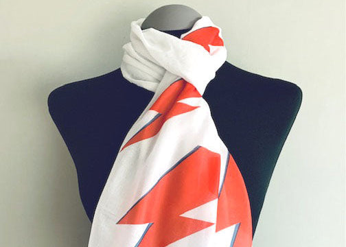 Mannequin wearing a white scarf with red and blue abstract patterns on a plain background