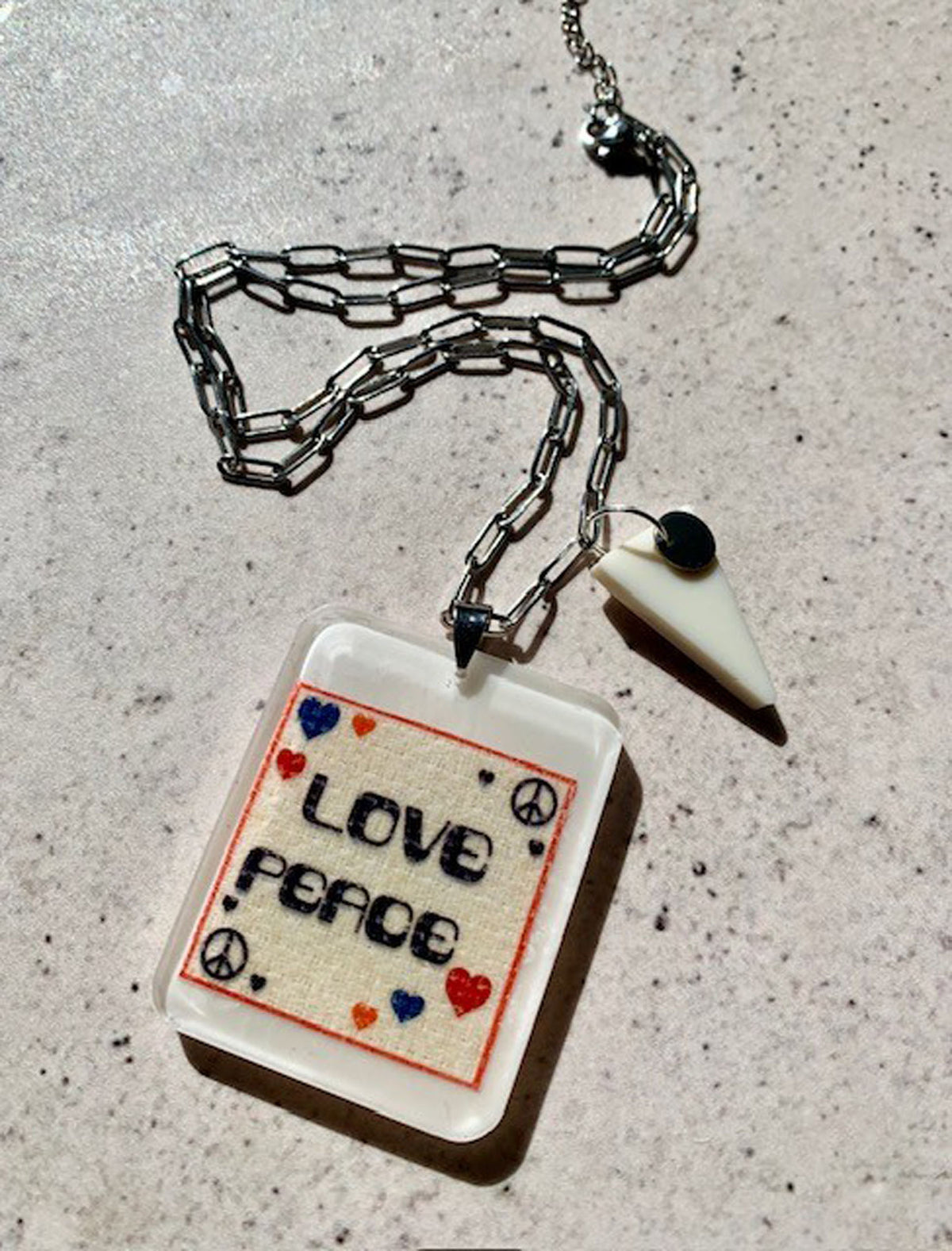 necklace with hand crafted ivory resin pendant with love and peace graphic artwork embedded