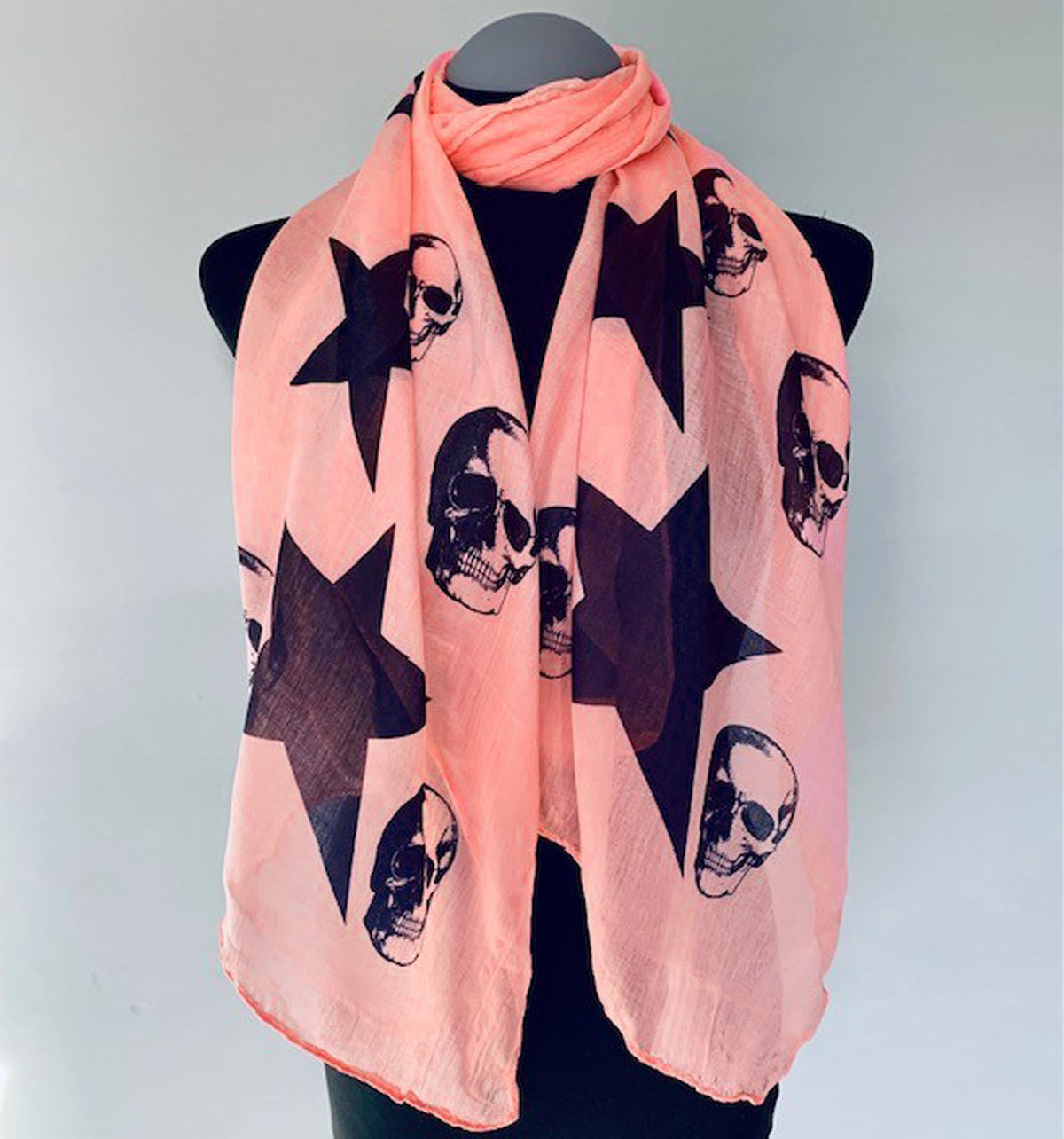 black skulls and stars print on a peachy pink long scarf